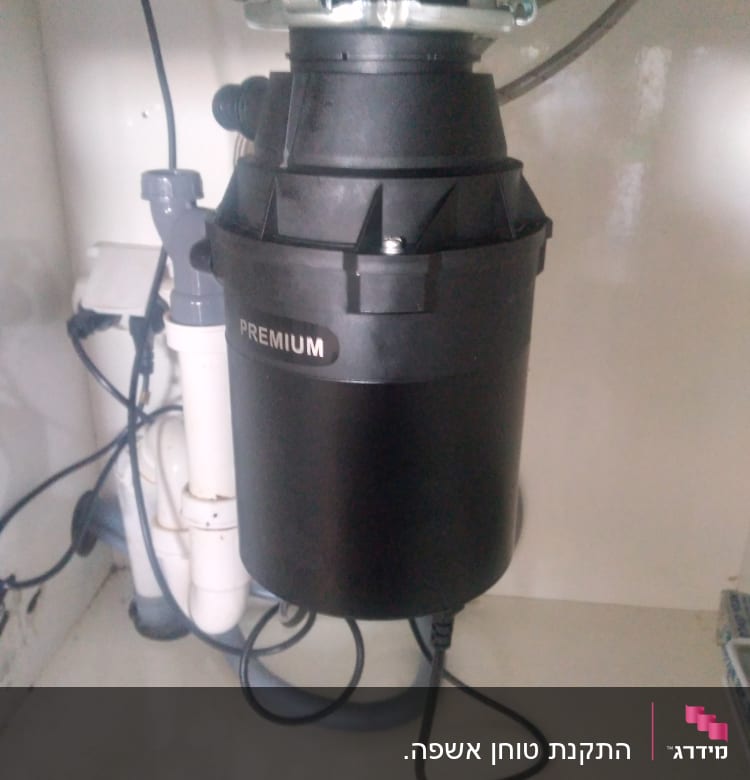 מכשיר טוחן אשפה מתחת לכיור עם צינורות חיבור